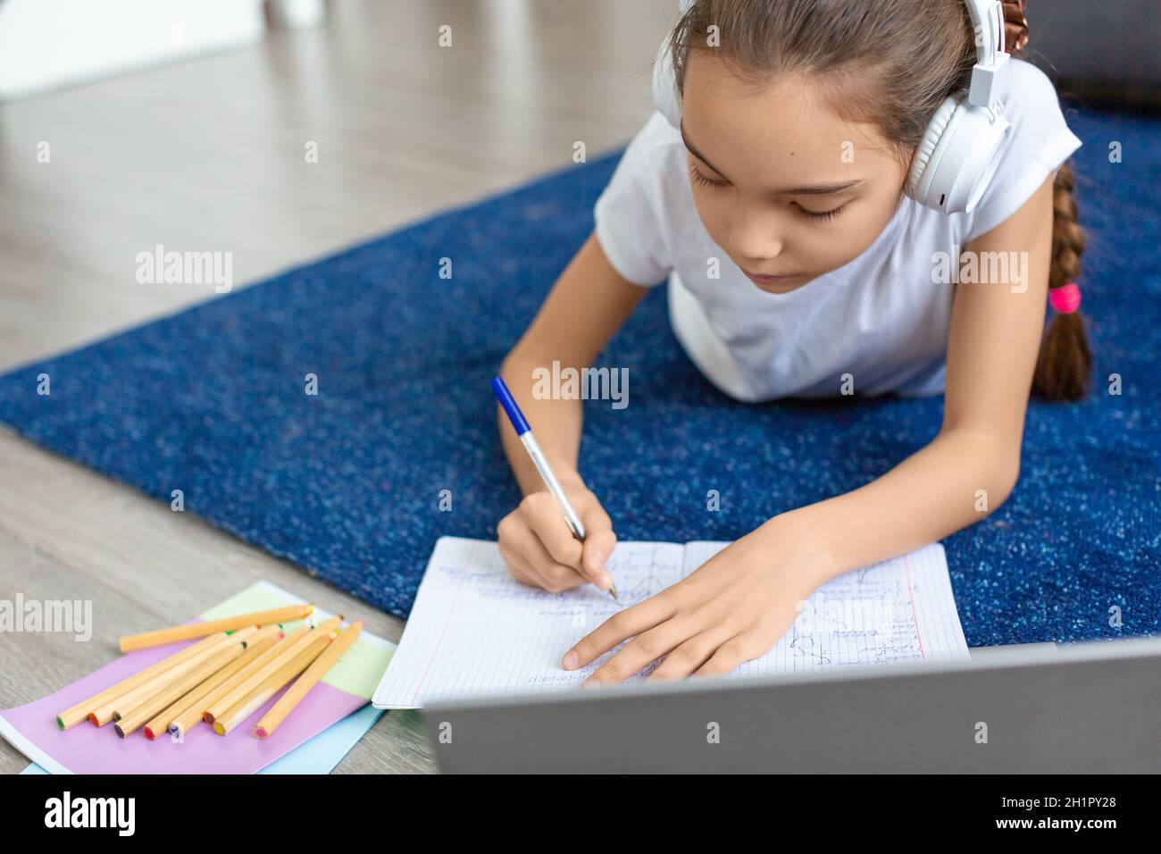 Schoolgirl doing homework online in front of a laptop monitor. She is ...