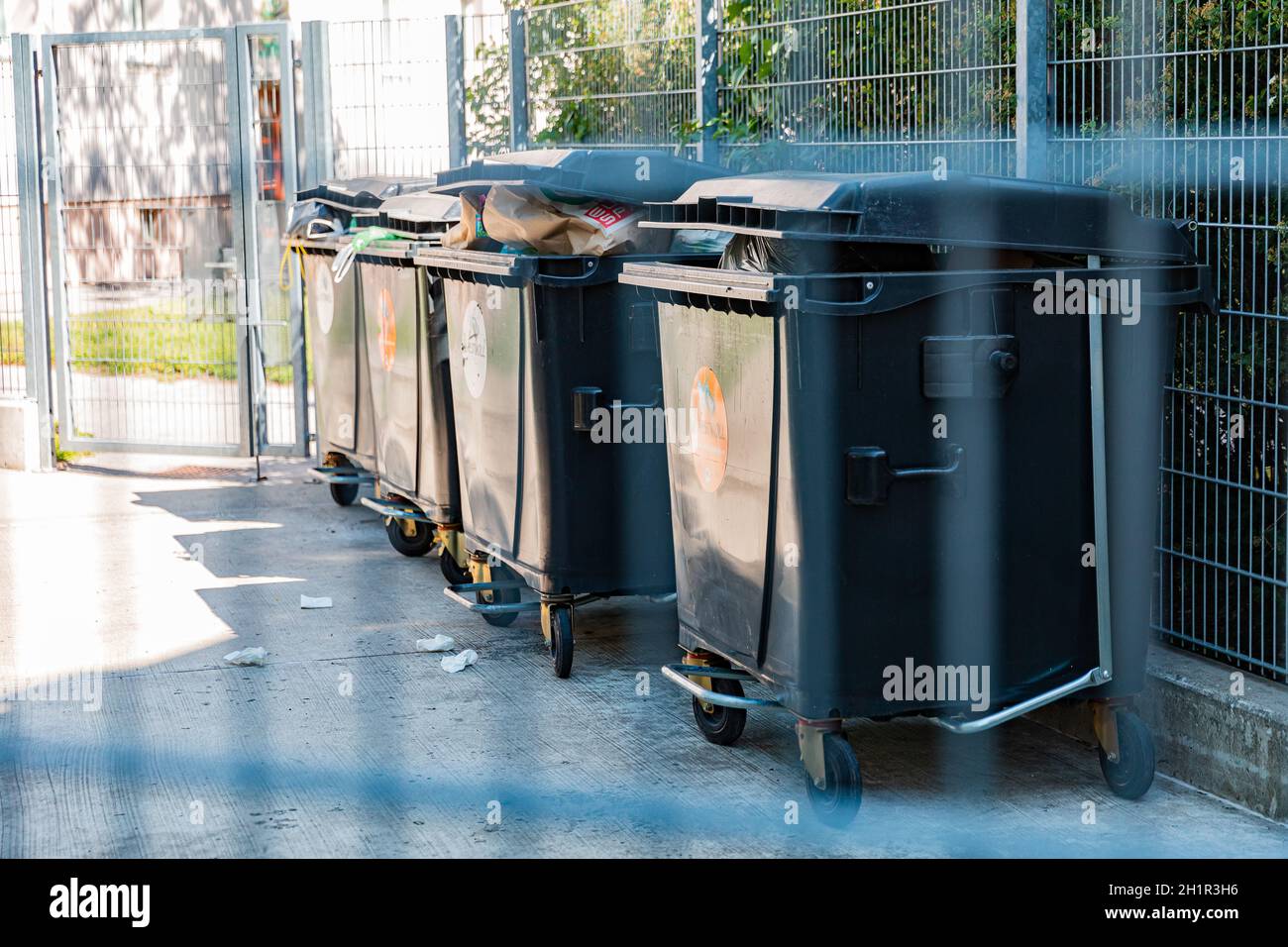 trash cans filled with rubbish behind barrier, scattered rubbish lies