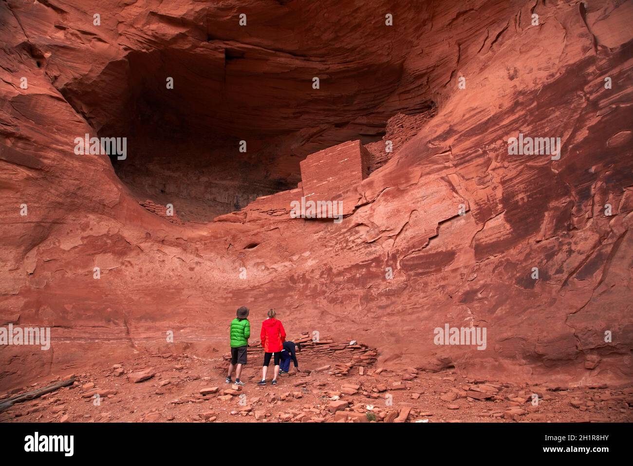 Tourists and ancient Anasazi cliff dwelling, Mystery Valley, Monument Valley, Navajo Nation, Arizona, USA (model released) Stock Photo