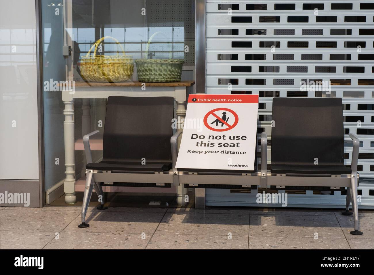 International Airport London Heathrow Terminal 2 – Three Seats Abreast with Public Health Notice „Do not use this seat – Keep your distance“ Stock Photo