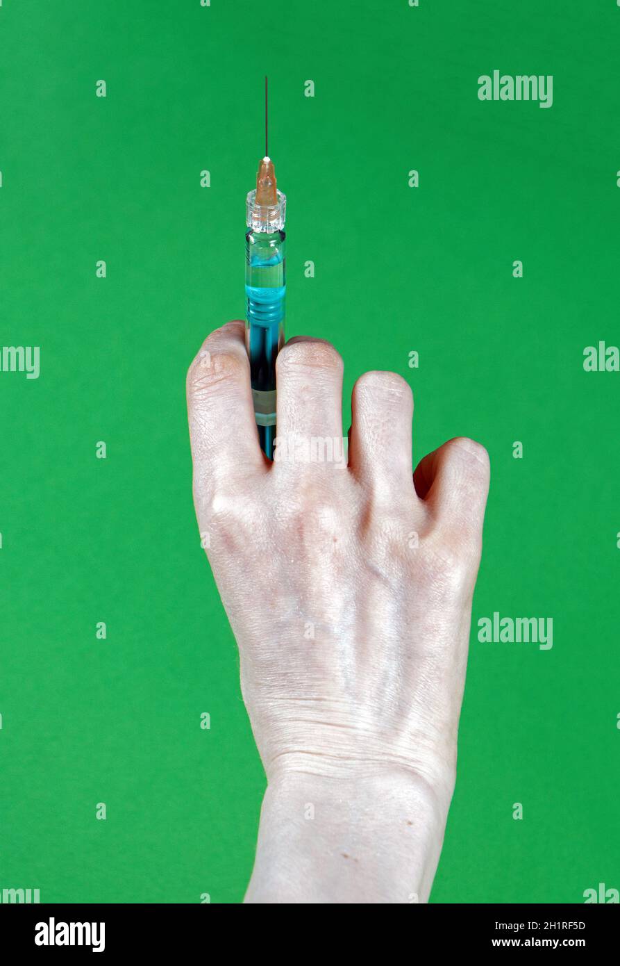 Female hand holding full syringe with needle without medical glove Stock Photo