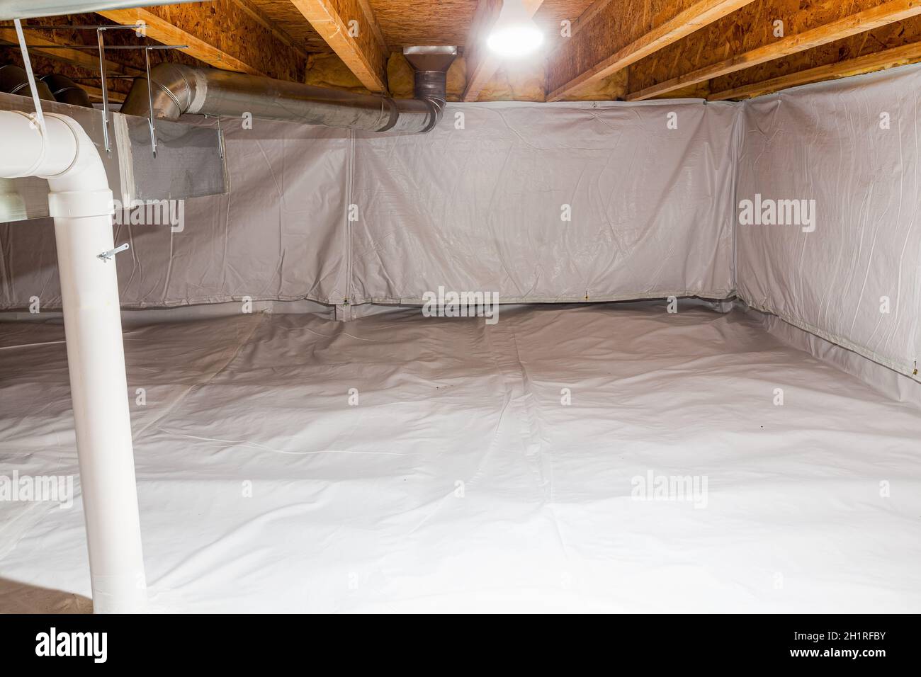 Crawl space fully encapsulated with thermoregulatory blankets and dimple board. Radon mitigation system pipes visible. Basement location for energy sa Stock Photo