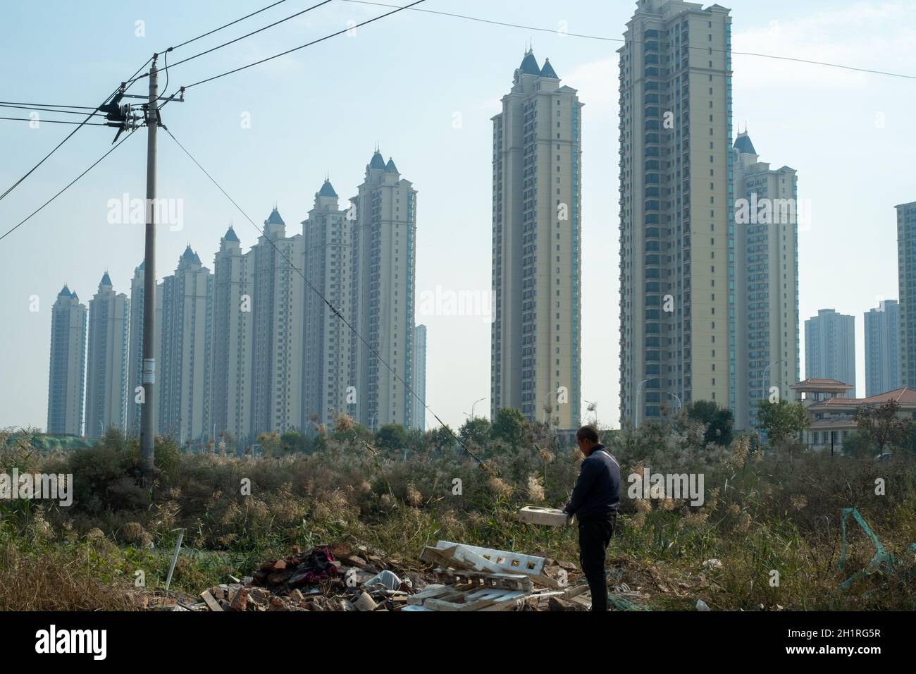 An elderly villager walks in front of the Evergrande residential properties in Wuqing district, Tianjin, China. 19-Oct-2021 Stock Photo