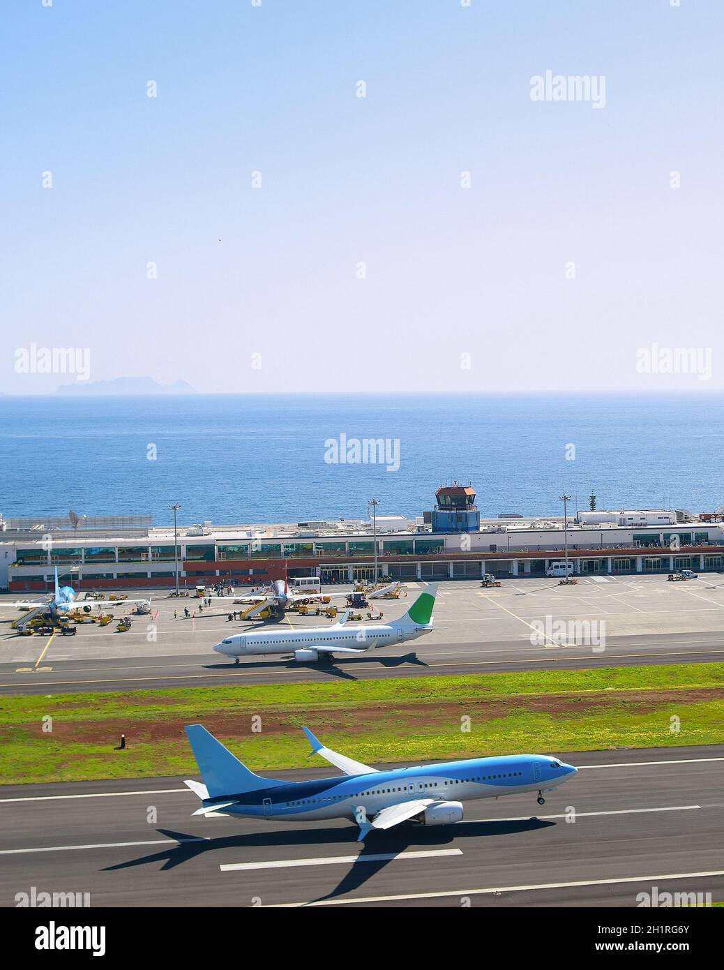 Airplane taking off runway of Madeira International Airport, sunny ocean view in background, Funchal, Portugal Stock Photo