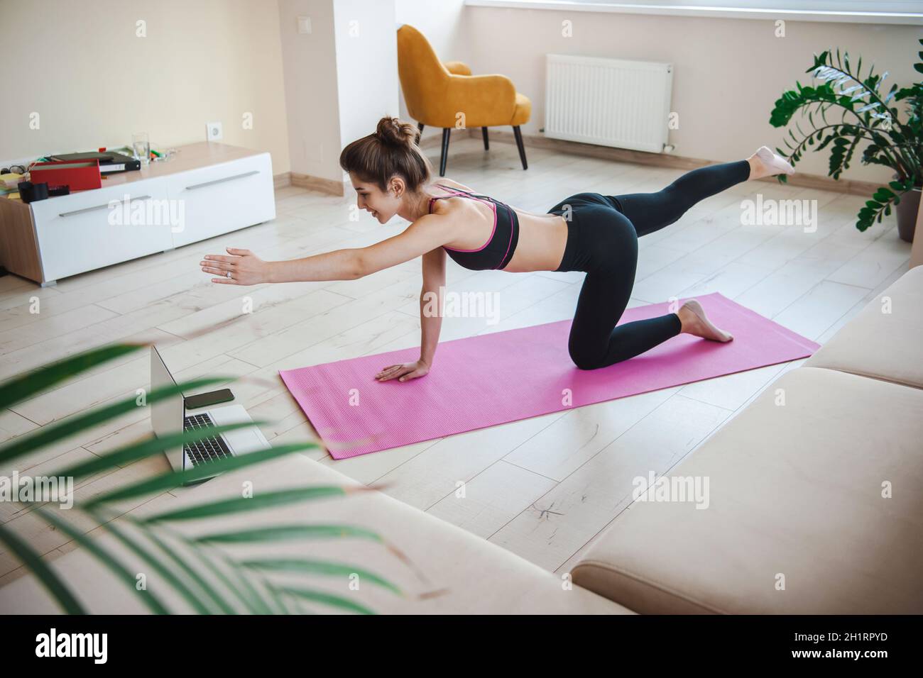Sporty woman doing online workouts isolated at home holding left