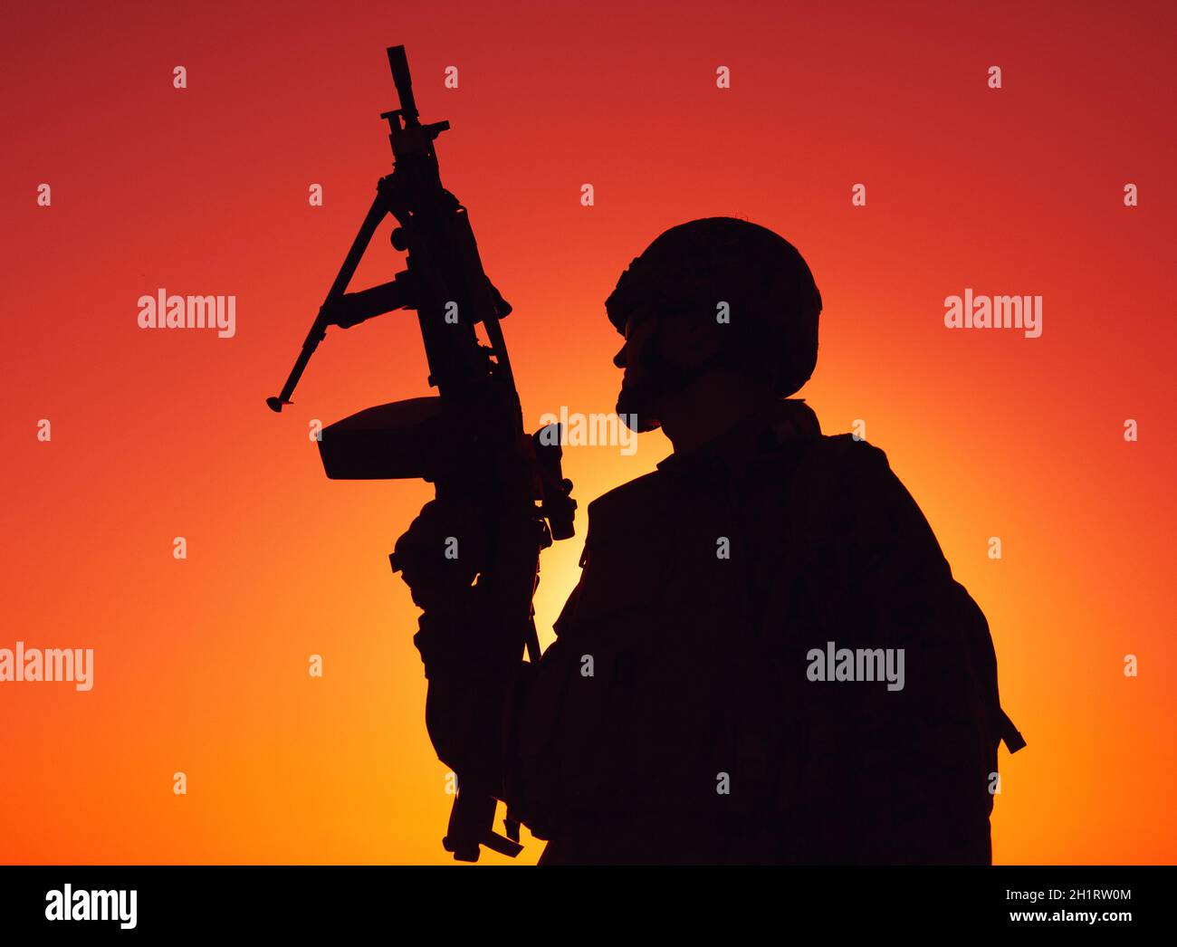 Silhouette of army soldier, special operations shooter armed light machine gun standing on background of ocean or sea horizon at sunset time. Coast gu Stock Photo