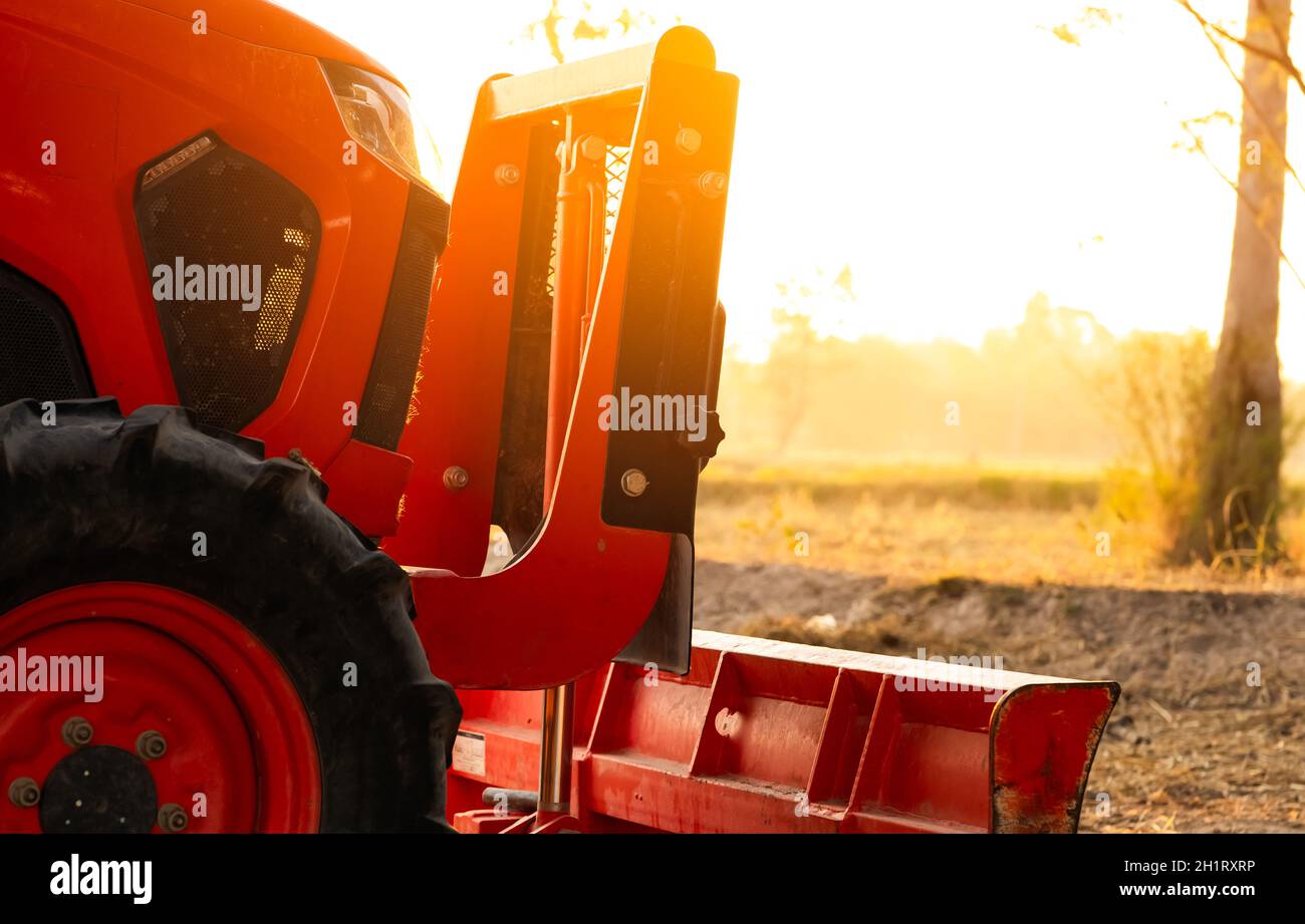 Orange tractor parked at rice farm in summer morning with sunlight
