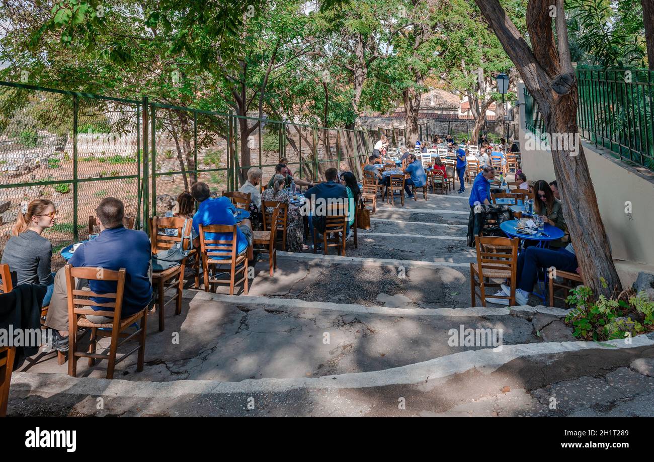 People enjoy refreshments at a traditional outdoor Greek cafe on the slop of the Acropolis Hill, in Plaka district. Stock Photo