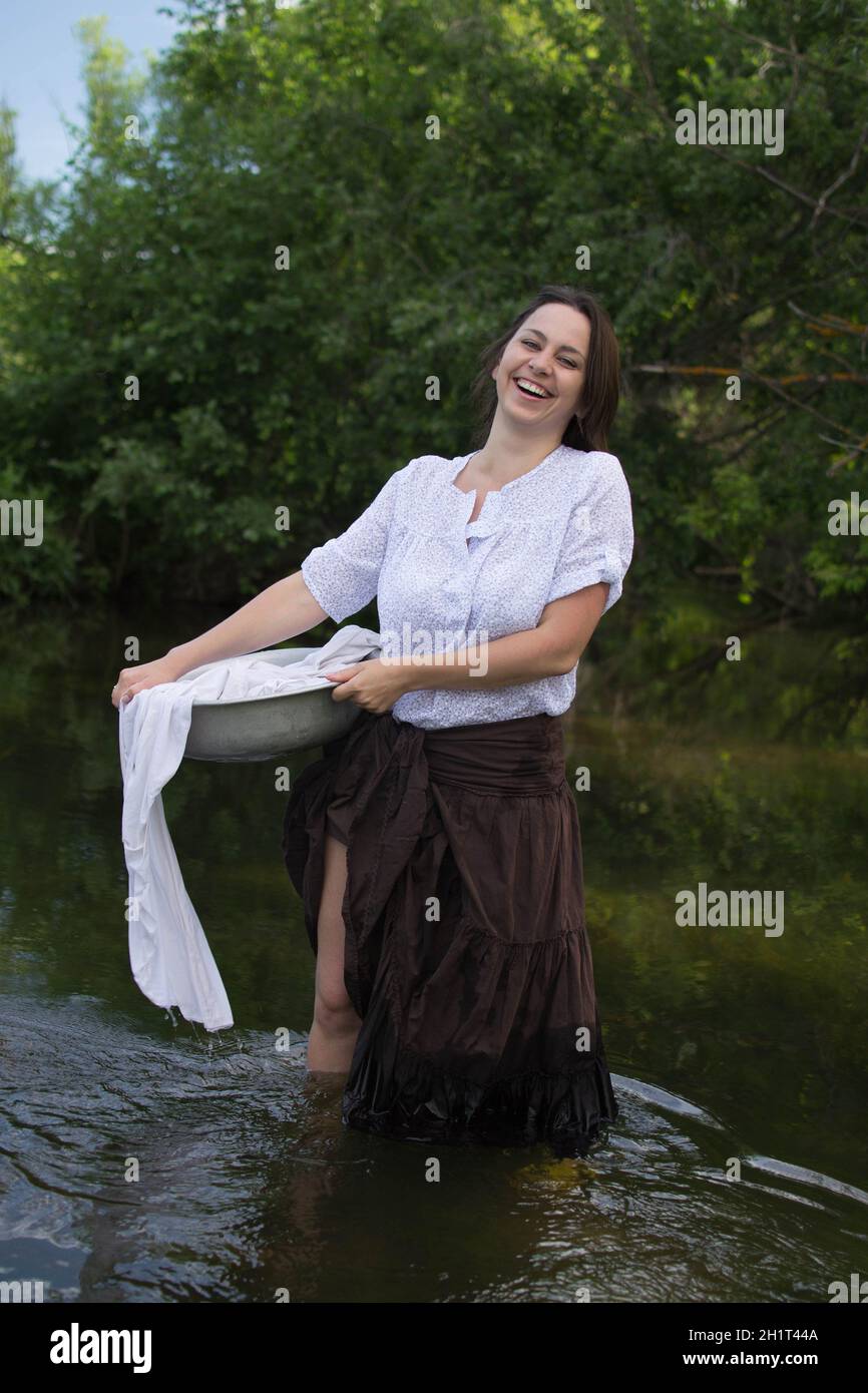 https://c8.alamy.com/comp/2H1T44A/peasant-woman-washes-clothes-in-the-river-near-the-forest-2H1T44A.jpg