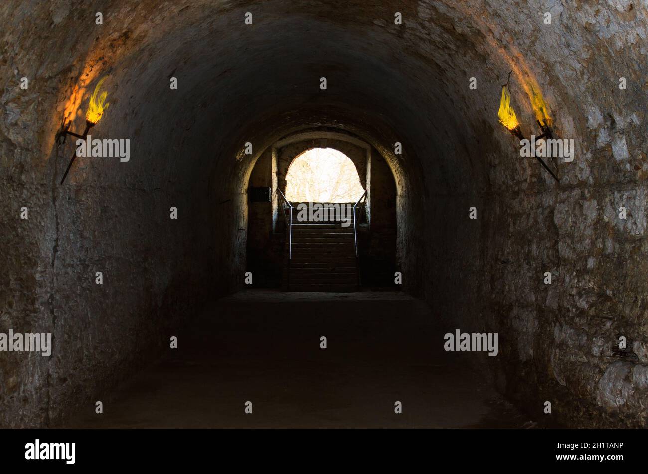 catacombs of the old castle illuminated burning torches. Stock Photo