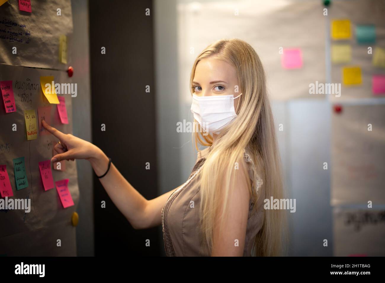Young women sticking post-its on an idea board. Brainstorming and organizing, whiteboard, chalkboard Stock Photo