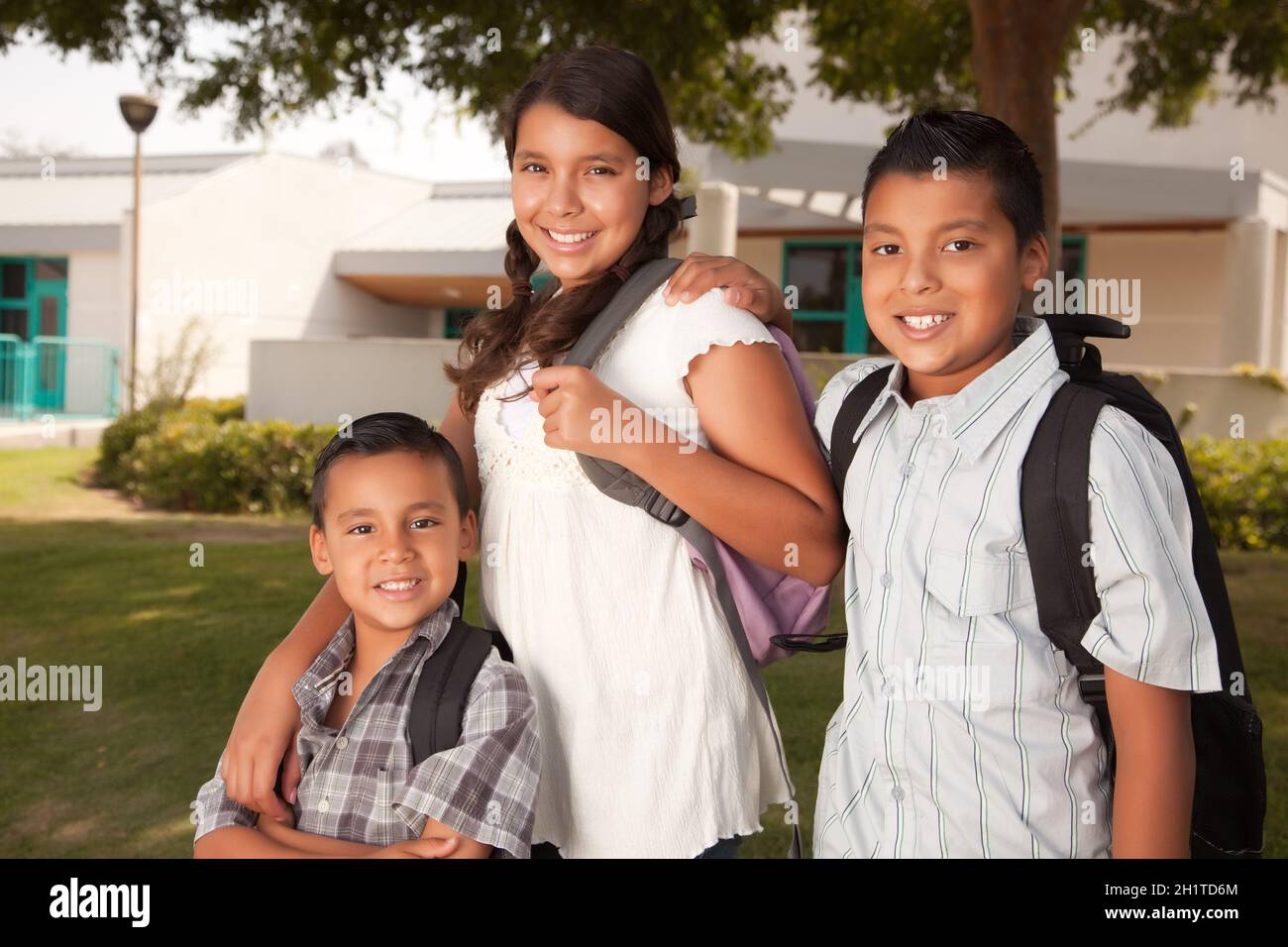Cute Brothers and Sister Wearing Backpacks Ready for School. Stock Photo