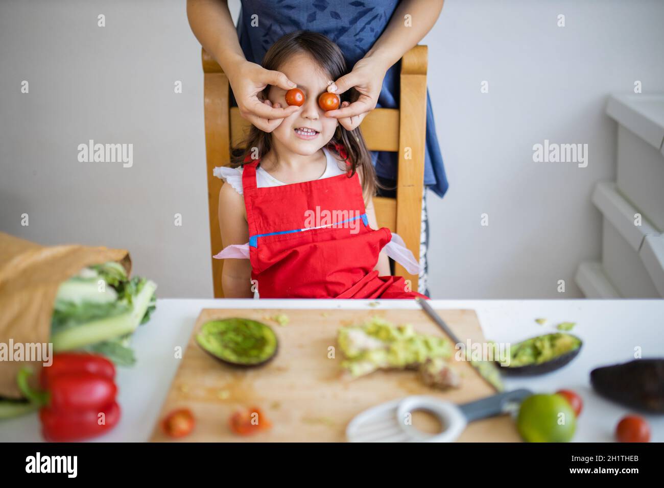 Happy mother and daughter at table playing with their food. Woman