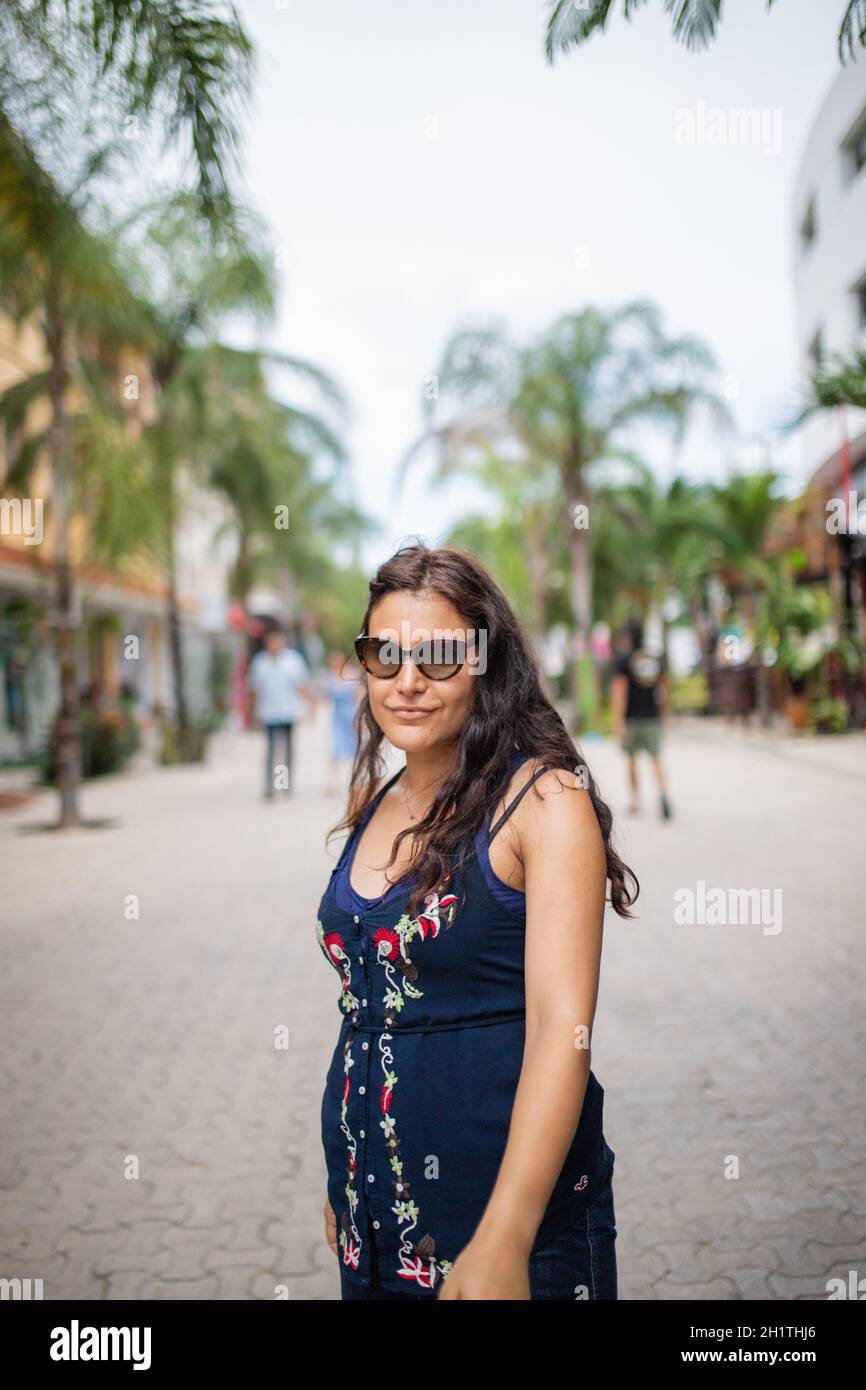 Beautiful woman wearing blue dress standing in a tropical street with ...
