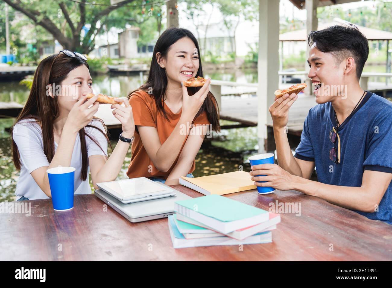 Students group woman and man eating pizza together with cheese delicious having fun and enjoy party at outdoor university, Education concept Stock Photo