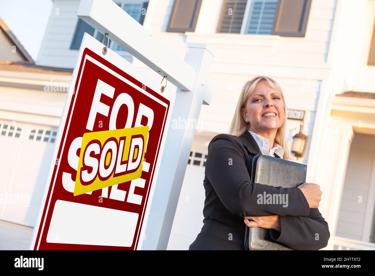 Female Real Estate Agent in Front of Sold For Sale Sign and Beautiful ...