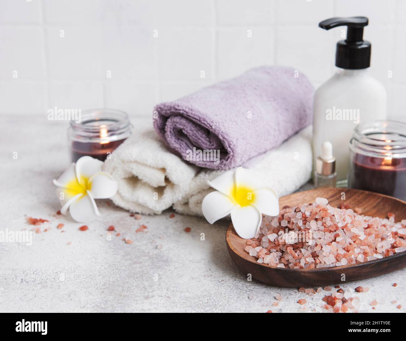 Spa set, essential oil, massage salt, candle and  frangipani flowers on gray concrete background Stock Photo