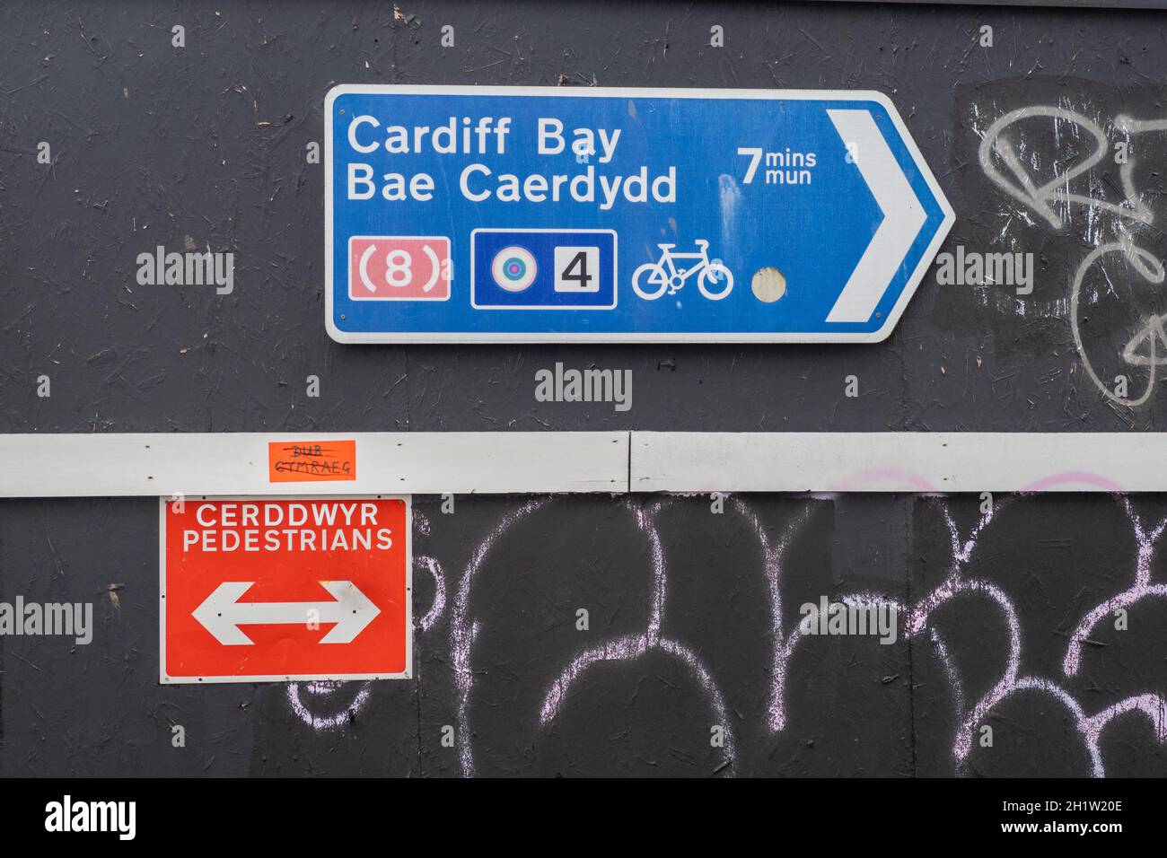 English / Welsh Street Signs – Cardiff Bay / Bae Caerdydd – and – Cerddwyr / Pedestrians on Bute Street – Cardiff Stock Photo