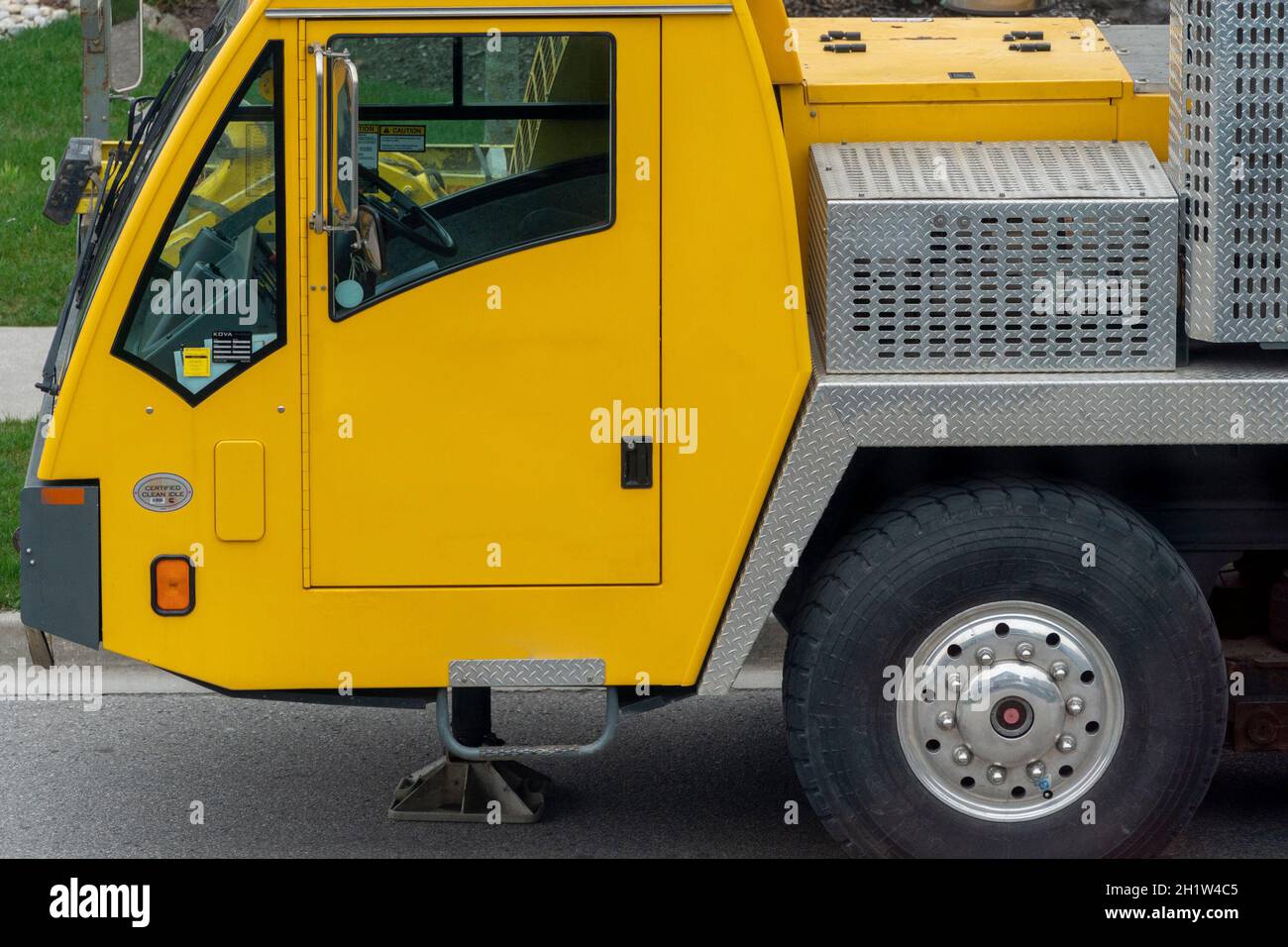 Fragment of a yellow truck crane cab, with a front wheel on the driver's side Stock Photo