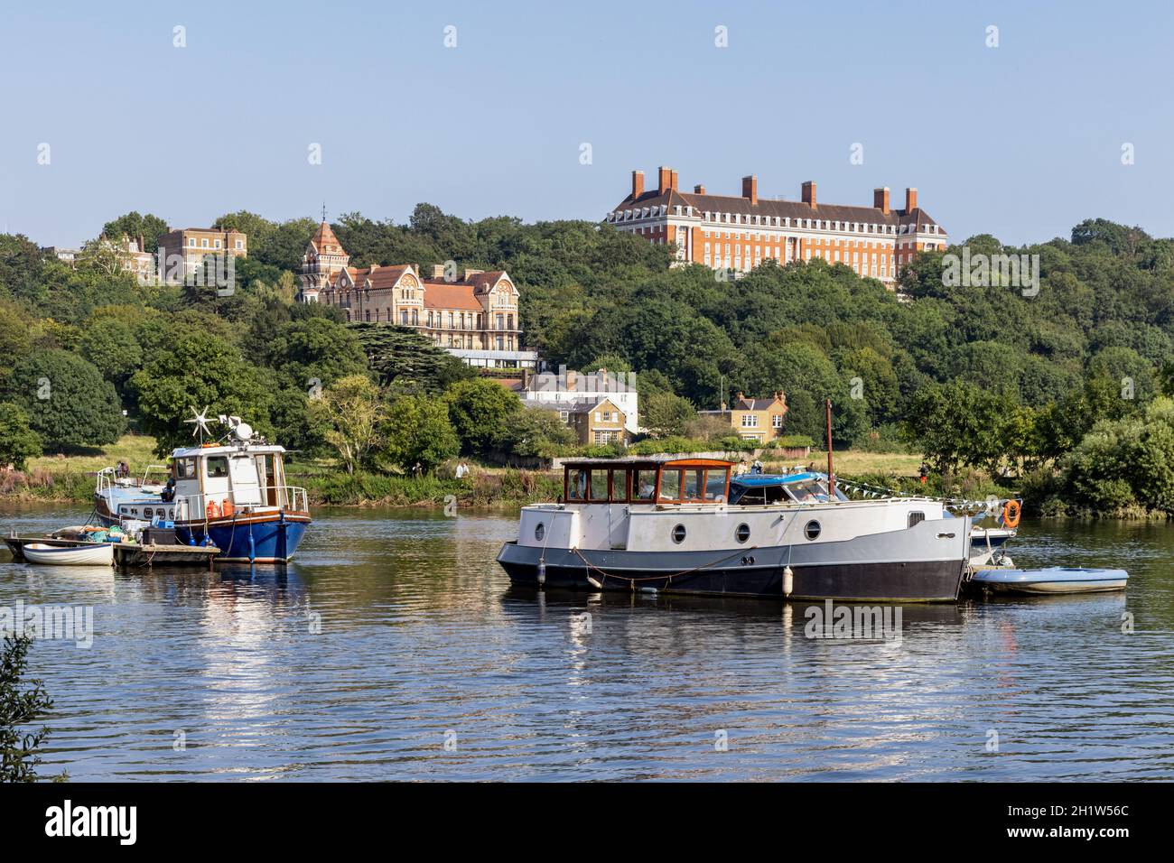 The River Thames from the Thames Towpath in the Borough of Richmond, with the Petersham Hotel and Royal Star & Garter Home buildings in the distance. Stock Photo