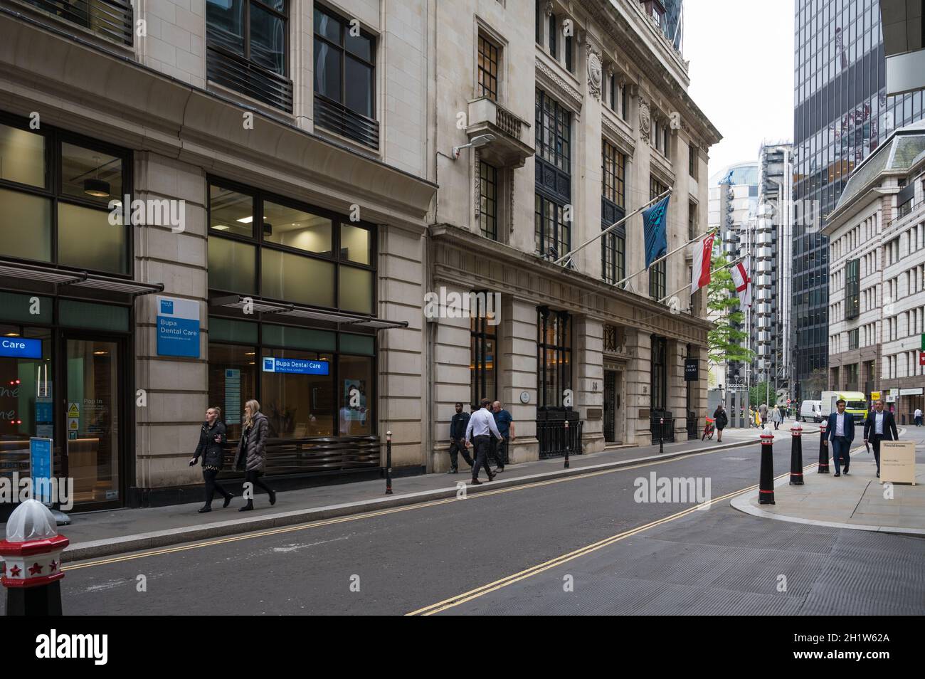 View along St. Mary Axe. Flags mounted on the facade of the original Baltic Exchange building. City of London, England, UK Stock Photo