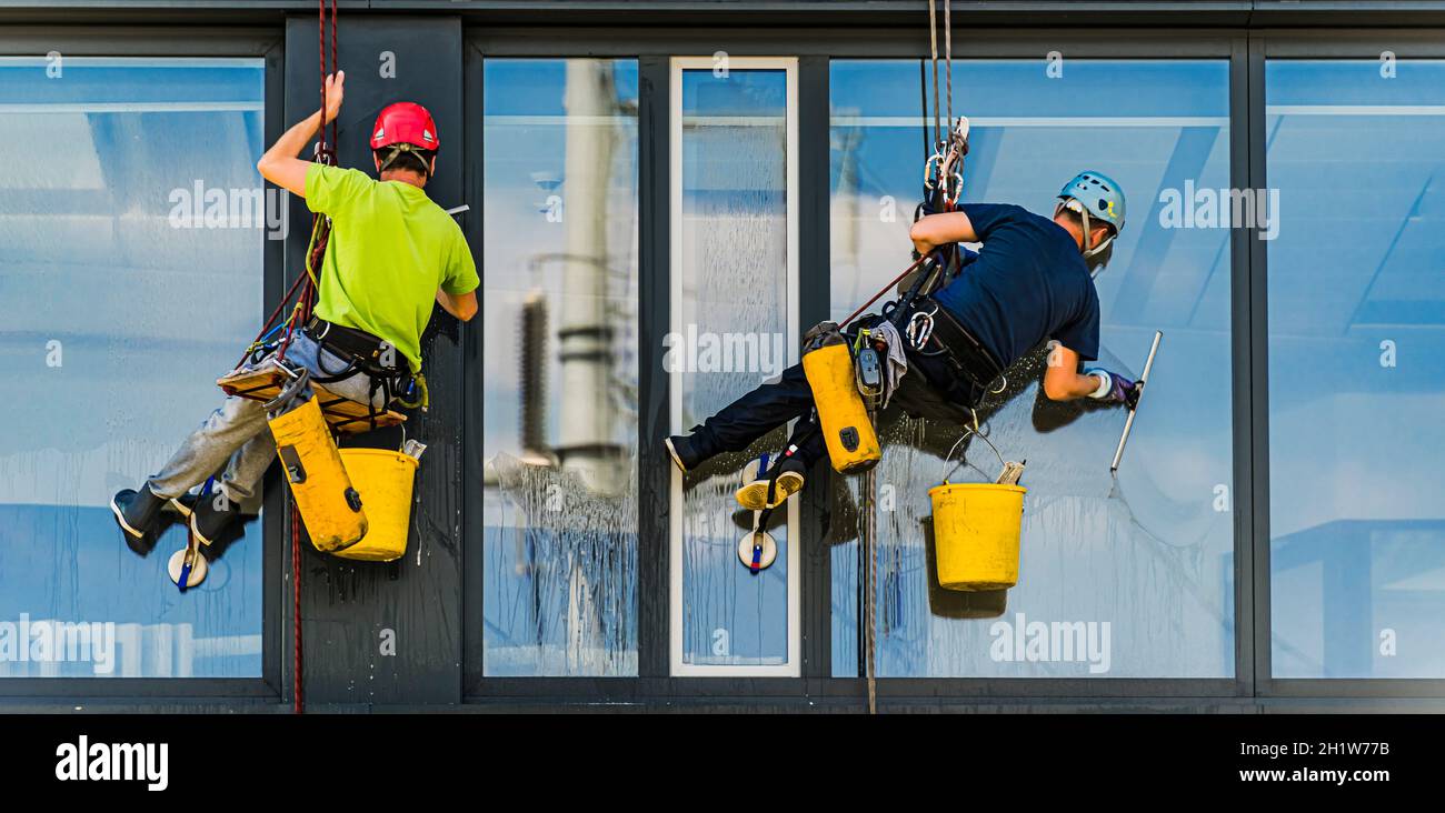 Two men cleaning windows on an office building Stock Photo