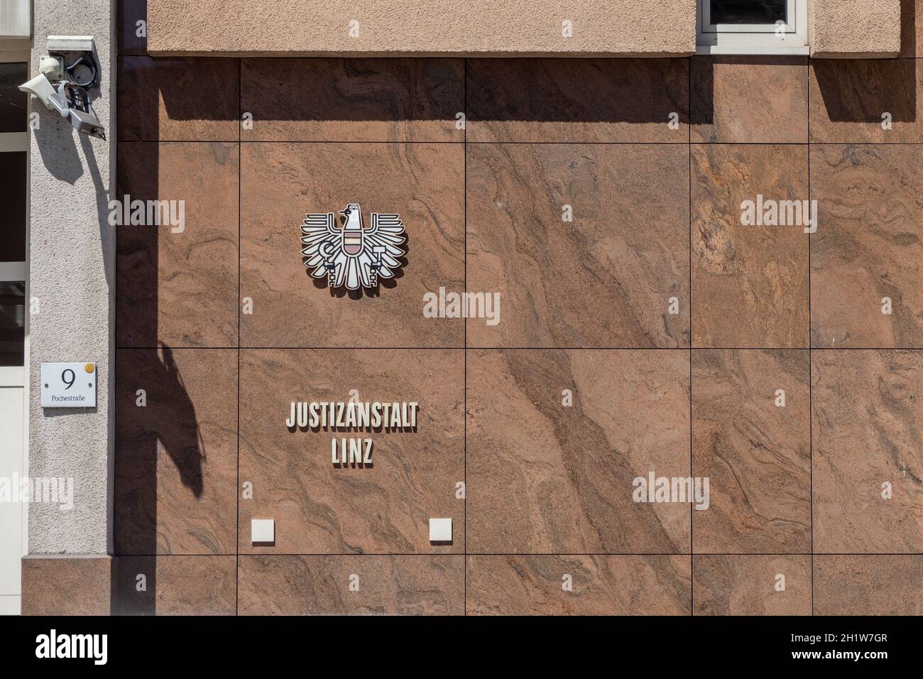 Inscription „Justizanstalt“ and a stylised Eagle - Austrian Coat of Arms – on the Wall of the Prison of the Regional Court - Linz Stock Photo