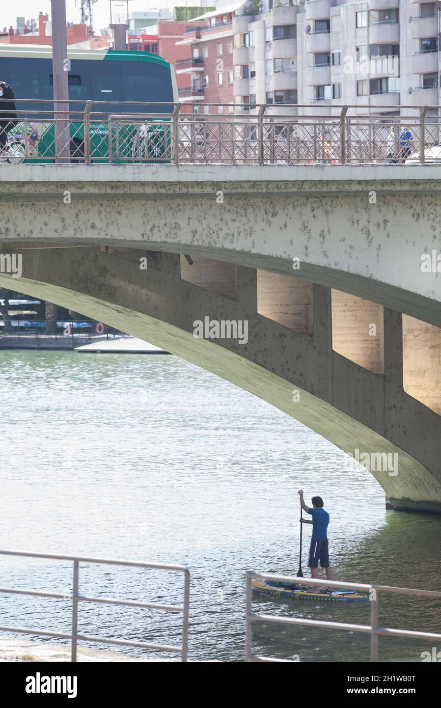 Paddle surfer under Triana Bridge of Seville, Spain. Guadalquivir River sports activities concept Stock Photo