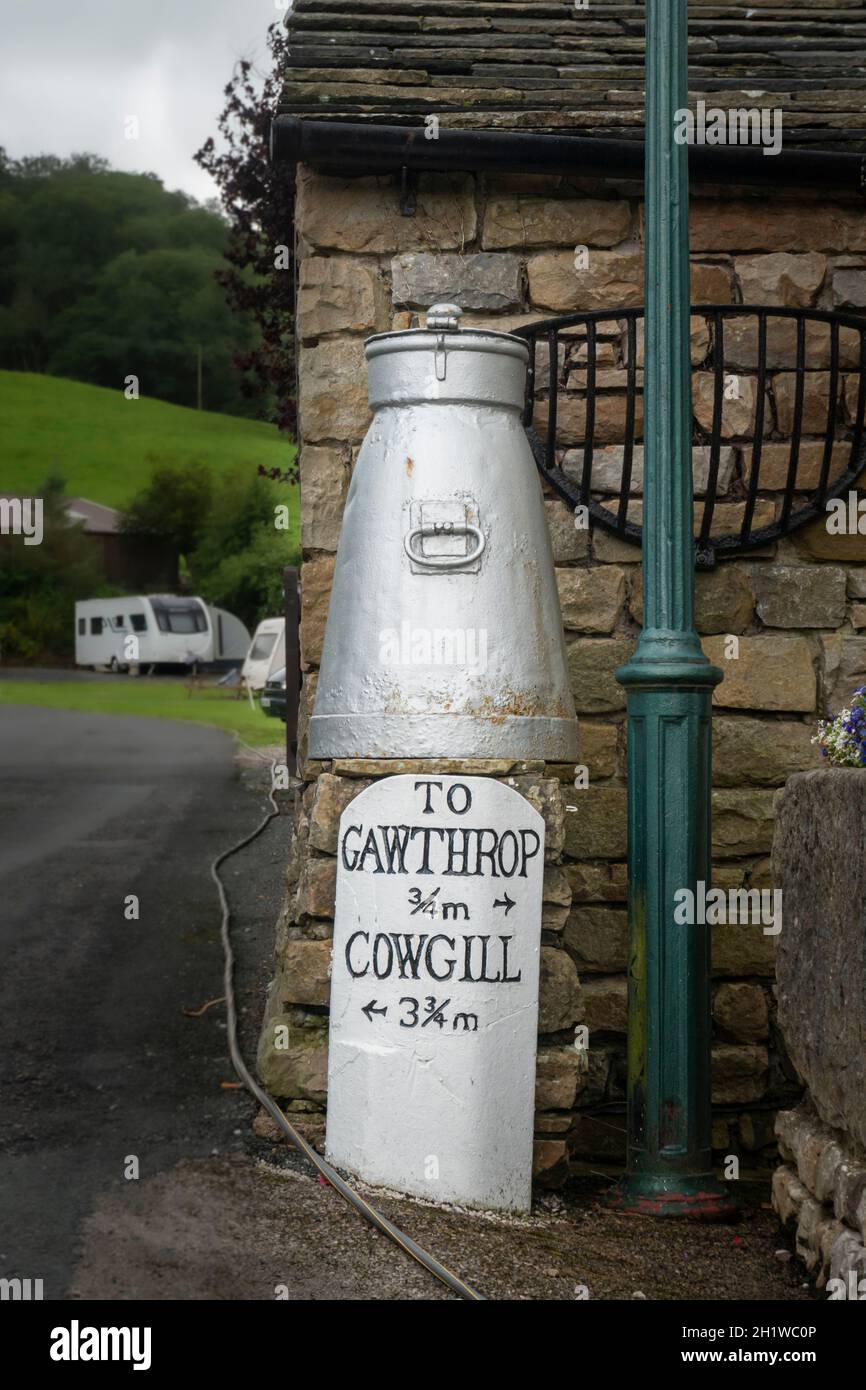 Directional sign and ancient milk churn in the village of Dent, Cumbria, UK Stock Photo