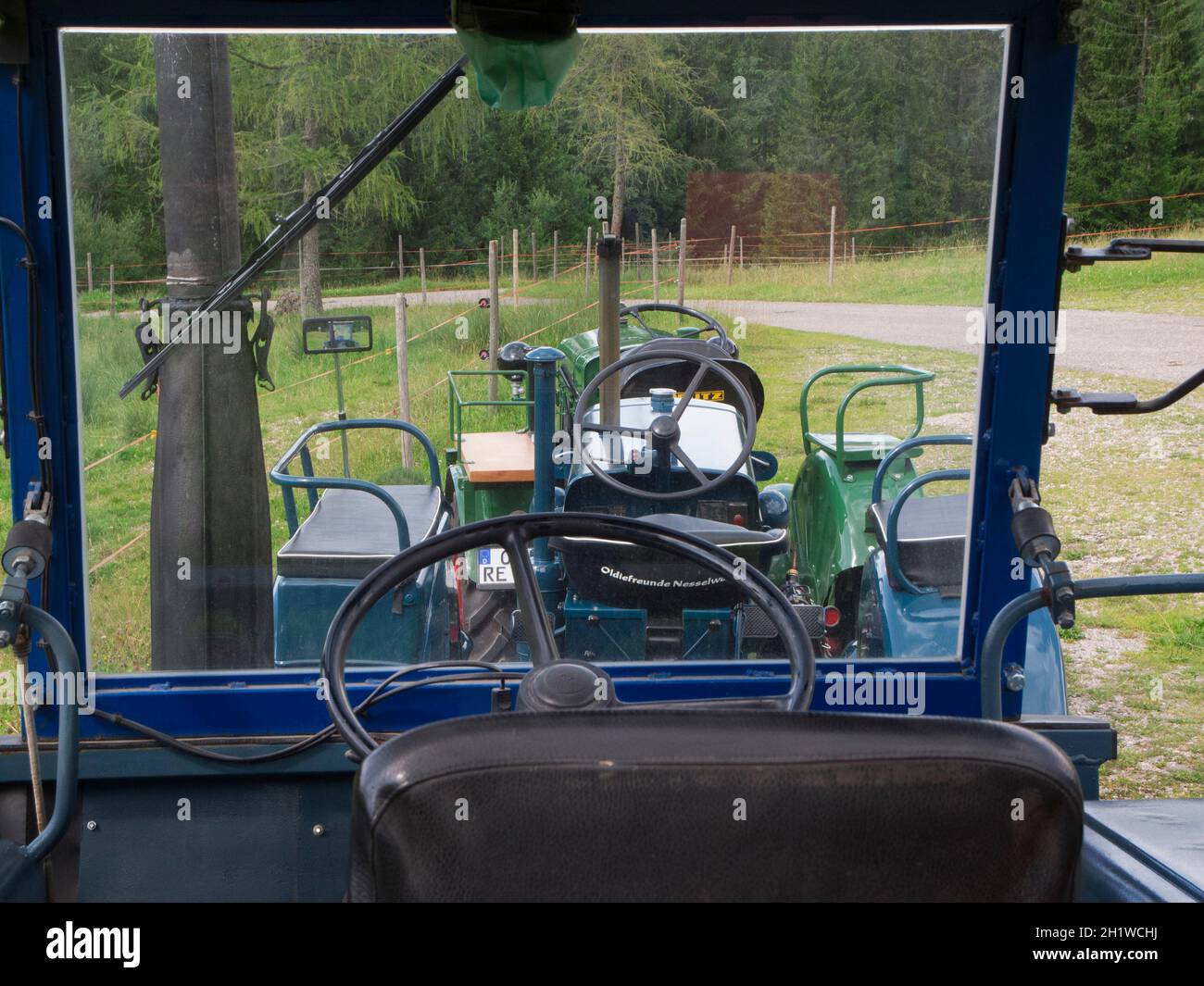 Innenansicht mit Blick durch die Windschutzscheibe eines restaurierten alten LANZ Traktors in grün mit karierten Sitzkissen nahe der Kleinstadt Nessel Stock Photo