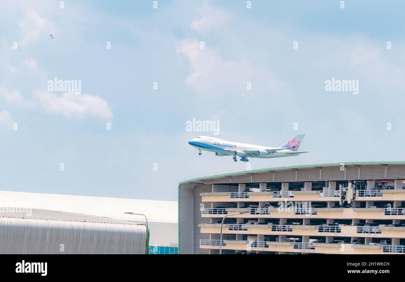 SAMUT PRAKAN, THAILAND-MAY 15, 2021 : China Airlines cargo plane flying above multi-story car park building of Suvarnabhumi airport in Thailand. Air l Stock Photo