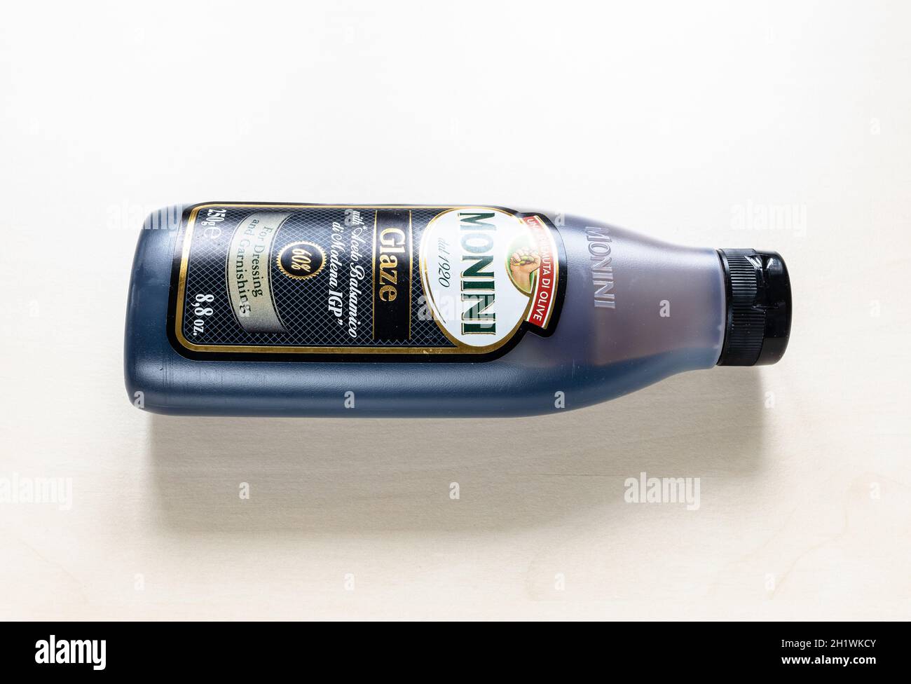 MOSCOW, RUSSIA - JUNE 10, 2021: lying bottle of Monini Glaze with Aceto Balsamico di Modena IGP on pale board. Glazes are the result of simmering the Stock Photo