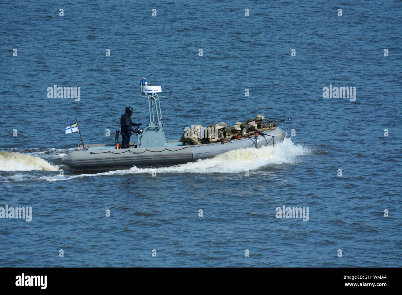 Miltary boat floating on the water, soldiers of Seaborne Special Forces aboard armed with machine guns. Military parade dedicated to Independence Day. Stock Photo