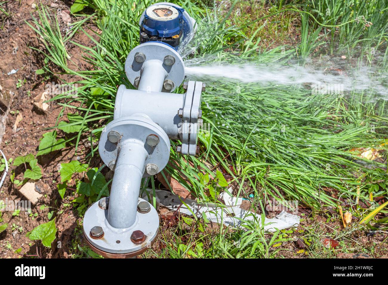 Water valve meter high pressure broken gaskets on bolted flanges spraying onto grass roadside