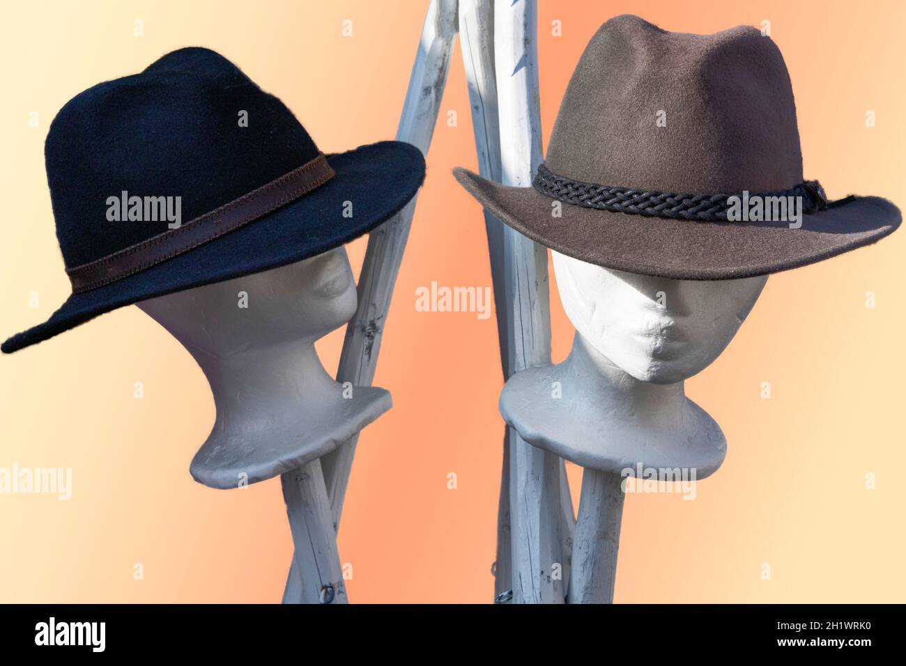 Human like dolly heads with hats against a light colored background Stock Photo