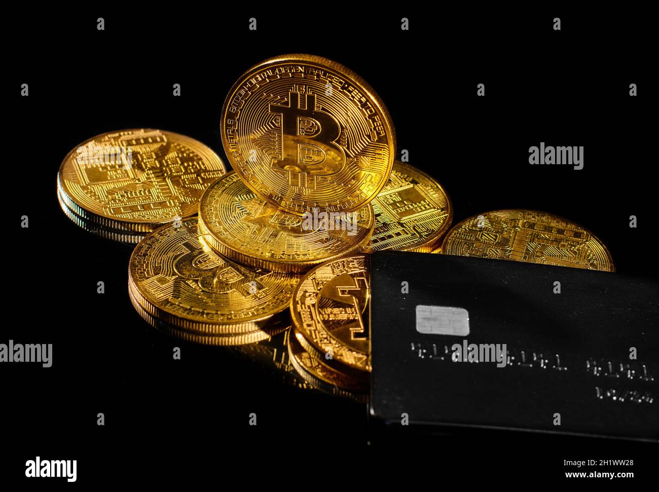 Leader in cryptocurrency BTC and bitcoin rewards card against black surface. Golden coin with bitcoin logo and credit card . Decentralized digital cur Stock Photo