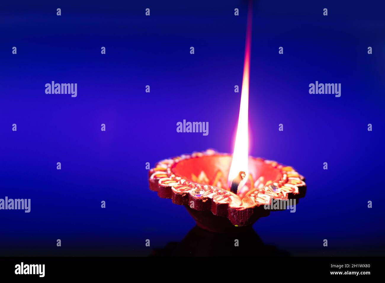 Handcrafted Eco Friendly Clay Diya Deep Dia Glowing With Flowers On Blue Background. Indian Festival Theme For Diwali Pooja, Navratri, Dussehra Puja, Stock Photo