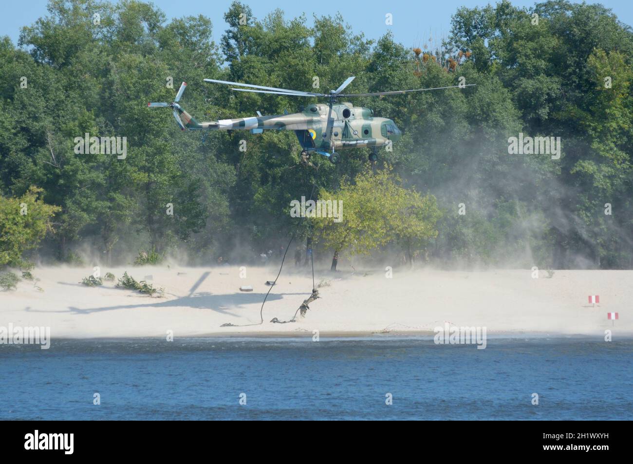 Military helicopter disembarking soldiers of Seaborne special forces on sandy beach attacking enemy, training. Stock Photo