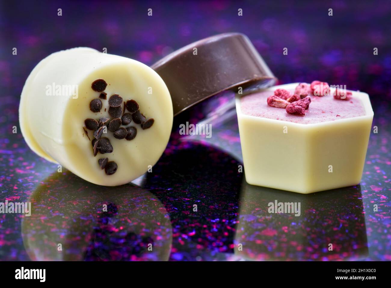 Close up of luxury continental or Belgian assorted chocolates on purple and pink speckled background Stock Photo