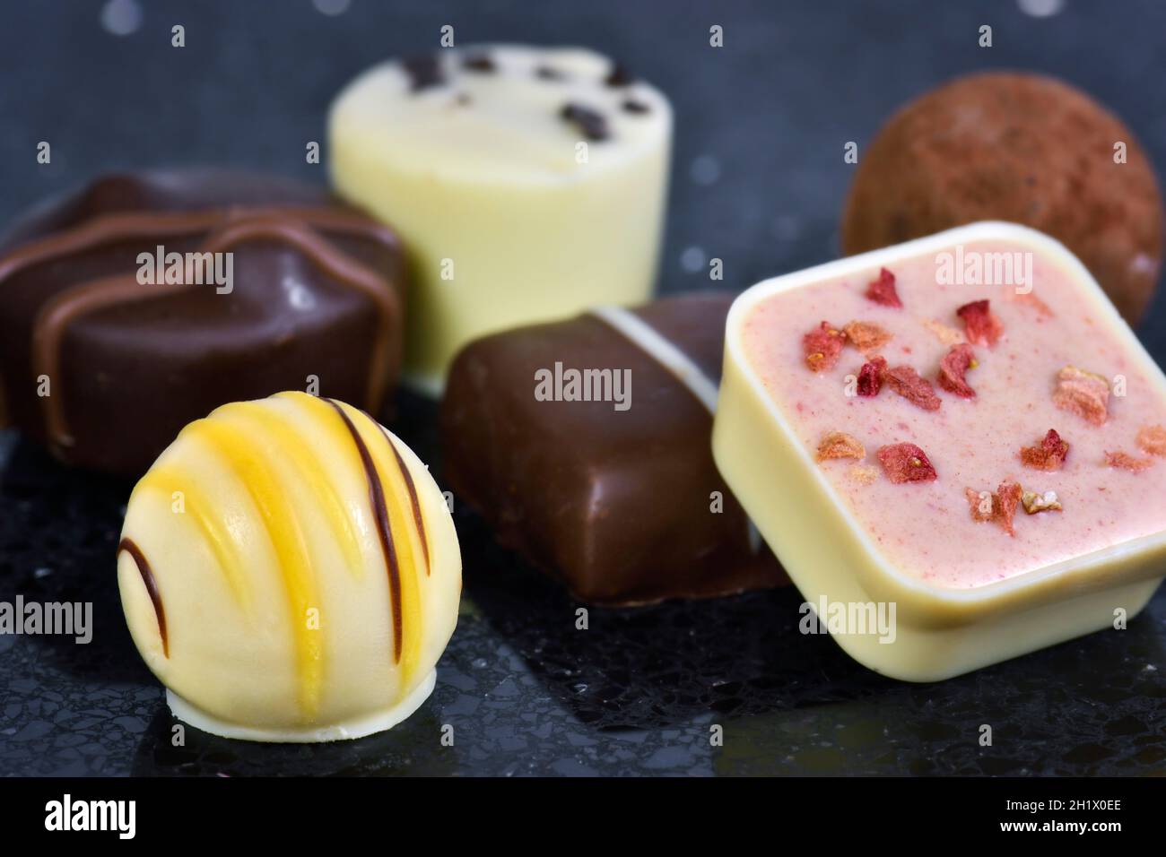 Close up of luxury continental or Belgian assorted chocolates on black worktop background Stock Photo