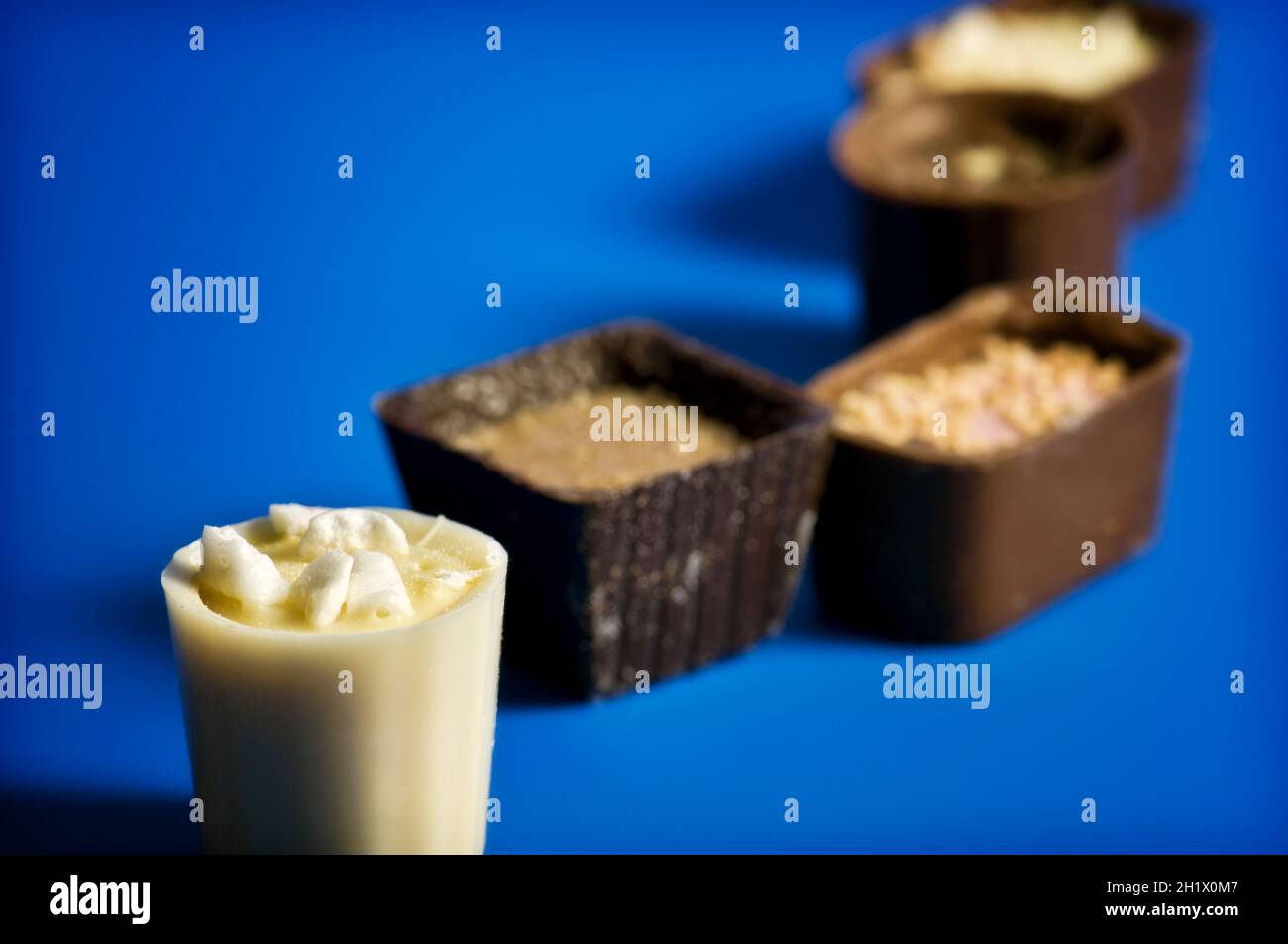 Close up of a line of luxury continental or Belgian assorted chocolates on dark blue  background Stock Photo