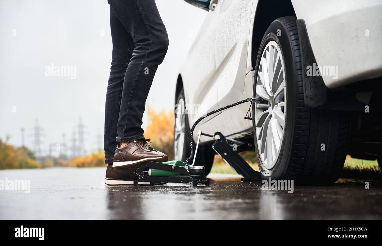 Close up of male legs in gray jeans inflating flat tire with air