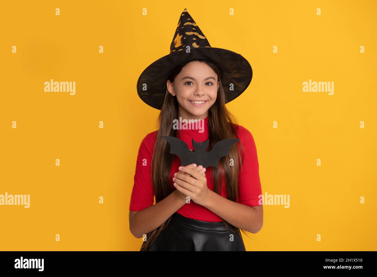 happy kid with bat wearing witch hat on yellow background, witchery Stock Photo