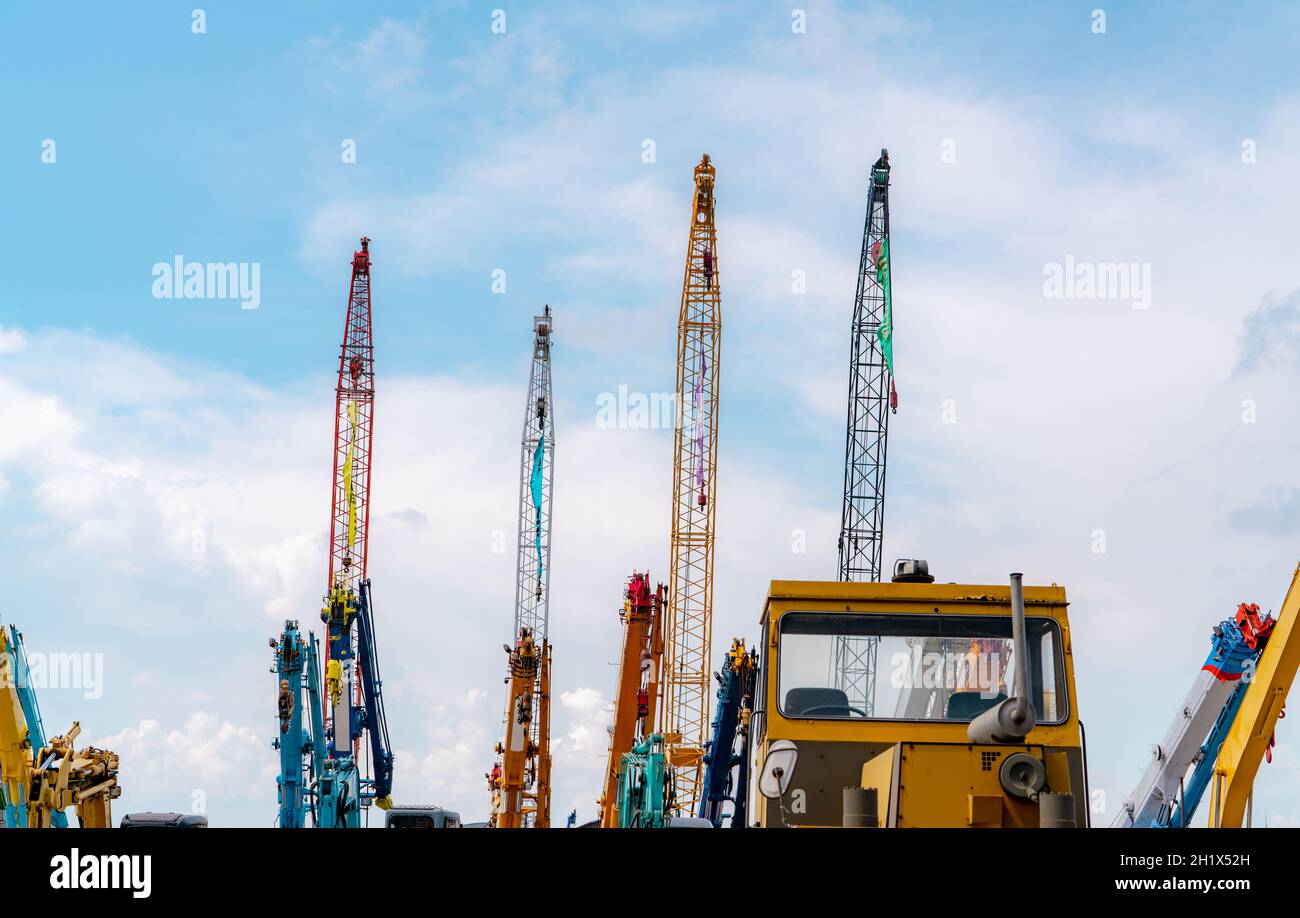 Crane against blue sky and white clouds. Real estate industry. Red and yellow crawler cranes use reel lift-up equipment. Crane for rent at the parking Stock Photo