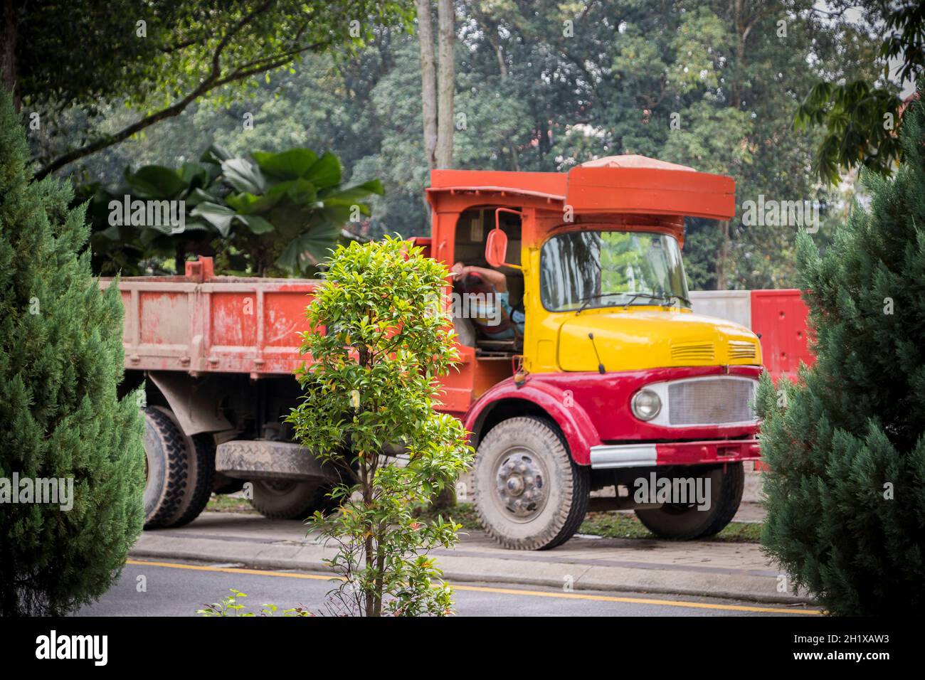 Driver sleeps in an old Asian truck made of wood in red and yellow. Kuala Lumpur, Malaysia. Stock Photo
