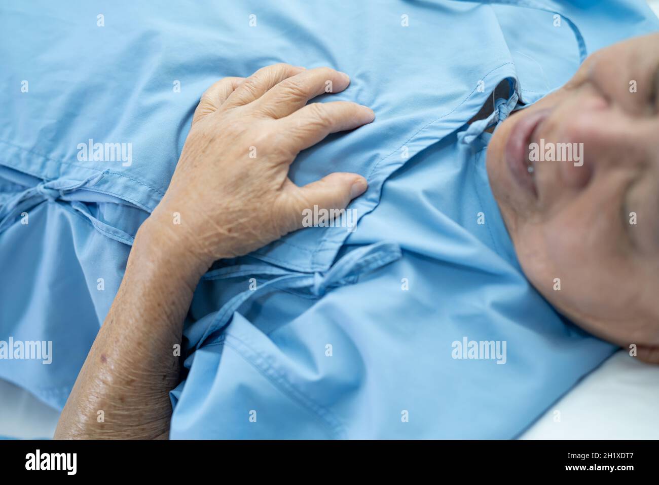 Asian senior or elderly old lady woman patient feel pain in the chest and heart on bed in nursing hospital ward; healthy strong medical concept. Stock Photo