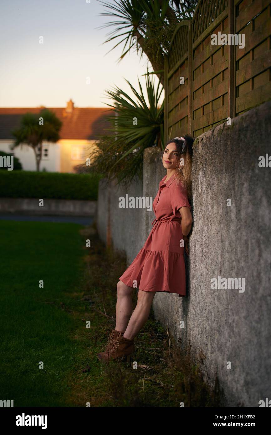 25yearold woman with pinup style, leaning on a stone wall Stock
