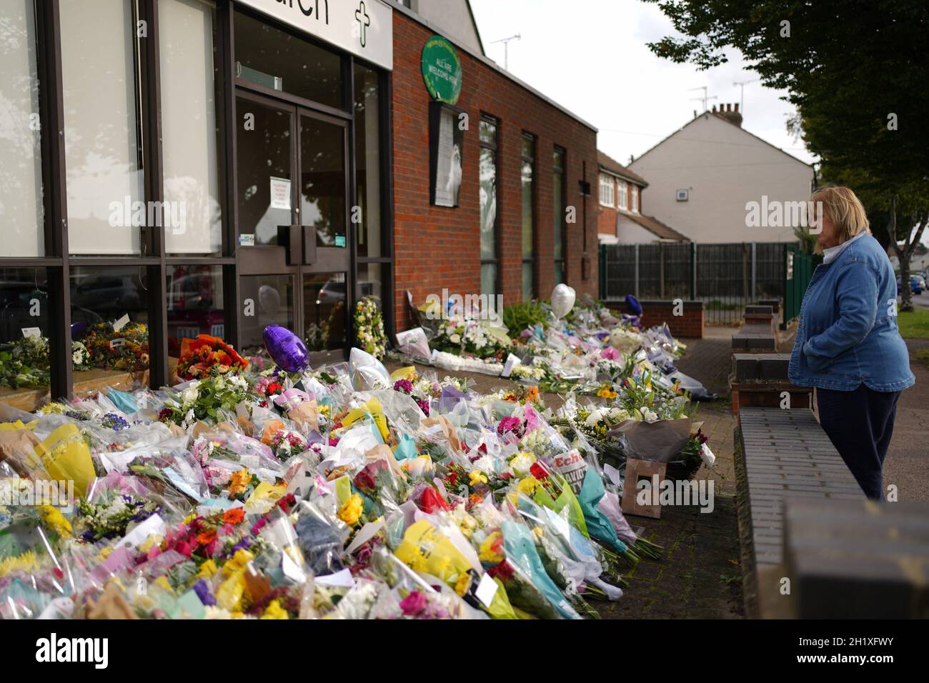 A woman looks at the floral tributes left outside the Belfairs Methodist Church in Leigh-on-Sea, Essex, where Conservative MP Sir David Amess was killed on Friday. Picture date: Tuesday October 19, 2021. Stock Photo