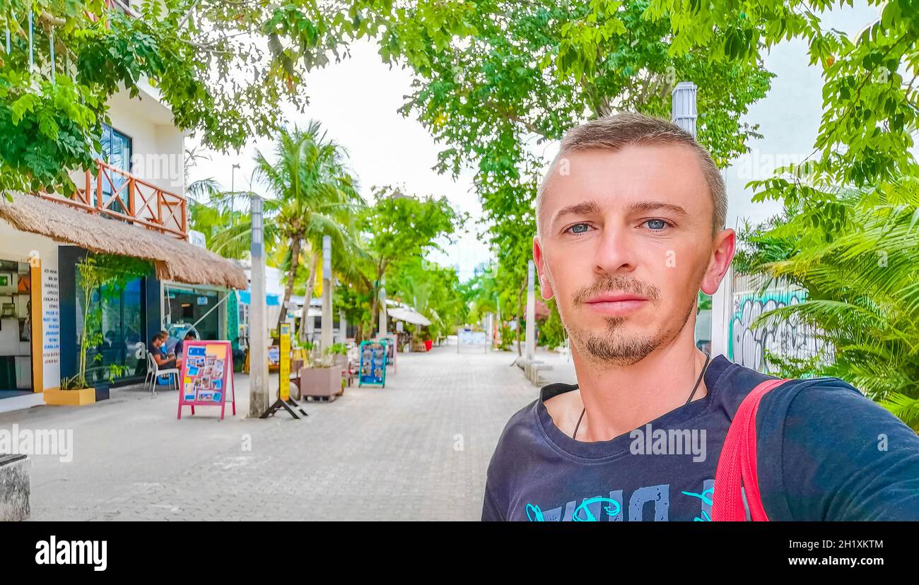 Male russian tourist traveler at typical street road and cityscape La Quinta Avenida with shops and building of Playa del Carmen in Mexico. Stock Photo
