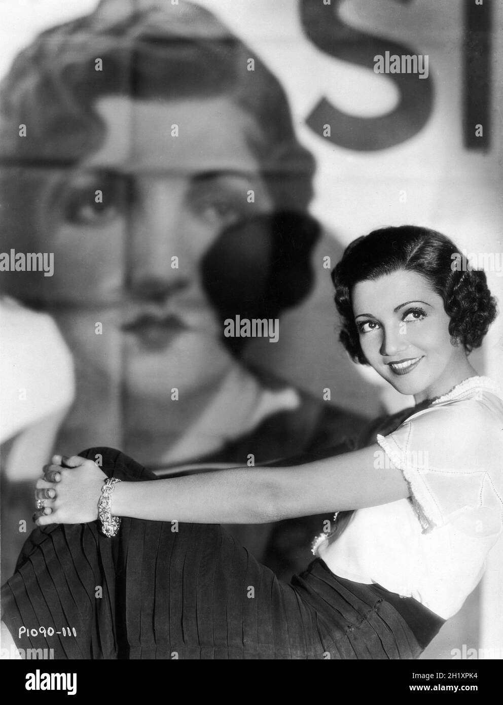CLAUDETTE COLBERT Portrait in front of large movie poster for her film TORCH SINGER 1933 directors ALEXANDER HALL and GEORGE SOMNES costume design Travis Banton Paramount Pictures Stock Photo